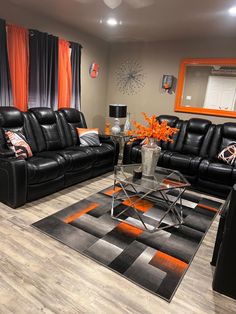 a living room with black leather furniture and orange accents