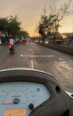 a person riding a motorcycle on a wet road at dusk with the sun setting in the distance