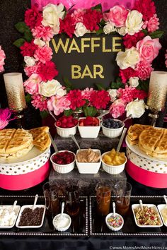 a table topped with waffles and desserts covered in pink carnations