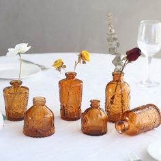 four brown glass vases sitting on top of a table next to plates and glasses