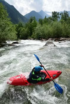 a man riding on top of a red kayak in the middle of a river