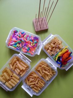 four plastic containers filled with different types of pastasticks and toothpicks on a green surface