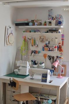 a sewing machine sitting on top of a white table next to a shelf filled with craft supplies