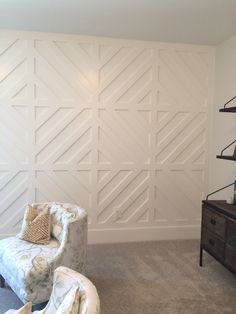 a living room with a couch and chair in front of a white paneled wall