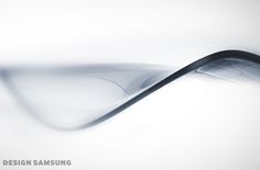 an abstract photo of a curved object in grey and white colors with the text design samsung above it