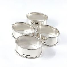 four silver pans sitting next to each other on a white surface