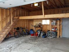 a garage filled with lots of different types of bikes and tools on the floor next to a stair case