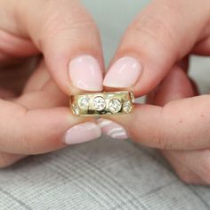 two hands holding a gold ring with three diamonds on the middle and one diamond in the middle