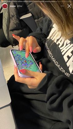 a woman sitting in front of a laptop computer holding a cell phone