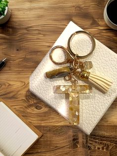 a cross keychain sitting on top of a table next to a notebook and pen