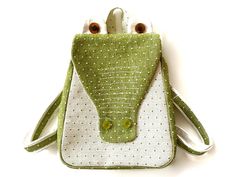 a green and white purse with two eyes on the front, one in the shape of a frog