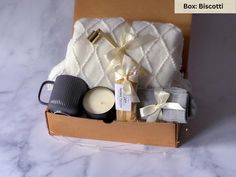 an open box containing candles, sweaters and other items on a marble countertop