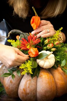 a person arranging flowers on top of a pumpkin