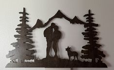 a metal wall hanging with a man and dog in the woods