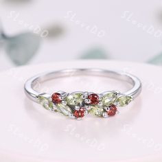 three different colored stones in a silver ring on top of a white plate with flowers