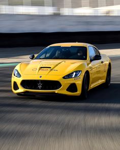 a yellow sports car driving down a race track