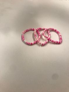 three pink and white bracelets sitting on top of a table