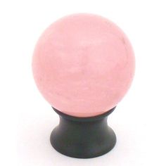 a black and pink knob on a white surface with a light pink ball in the center