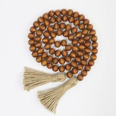 wooden beads with tassels are arranged on a white surface, including one bead