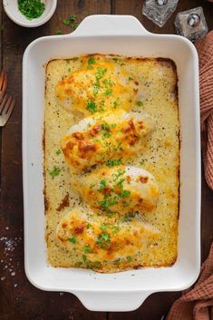 a casserole dish with chicken and cheese in it on top of a wooden table