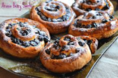 there are many baked goods on the plate and one is blueberry swirls with powdered sugar