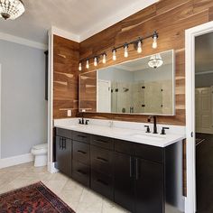 a large bathroom with two sinks and a mirror on the wall above it is decorated in wood planks