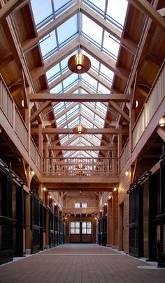 the inside of a building with lots of windows and wooden stalls on either side of it