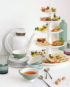 there are many plates and cups on the table with food in them that is stacked high