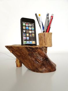 a cell phone sitting on top of a wooden stand next to pens and pencils