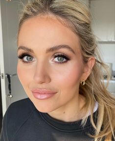 a woman with blonde hair and blue eyes is looking into the camera while wearing gold hoop earrings