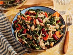 a bowl filled with vegetables and meat on top of a table next to a glass of water