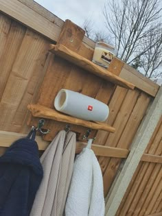 several towels are hanging on a wooden rack in front of a fence with a hair dryer and other items