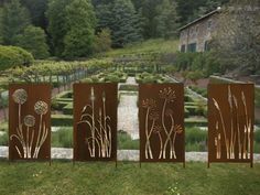 three metal art pieces sitting on top of a lush green field