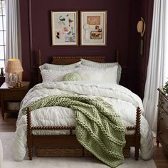 a bed with white comforter and pillows in a bedroom next to two pictures on the wall