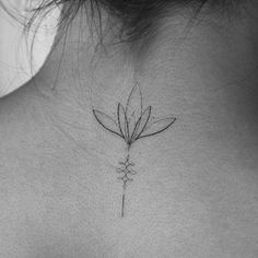 the back of a woman's neck with a flower tattoo on it