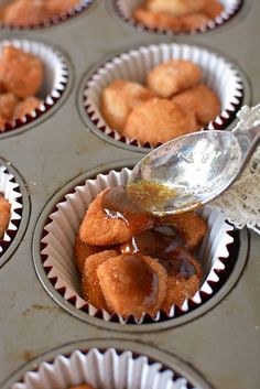 cupcake batter being drizzled with honey in a muffin tin filled with mini donuts