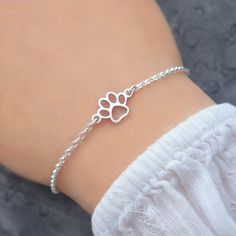 a woman wearing a silver bracelet with a paw print on it