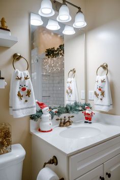 a bathroom decorated for christmas with white towels and reindeer decorations on the sink, along with other holiday items