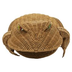 an animal made out of wicker sitting on top of a white surface with green eyes