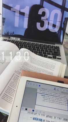 an open laptop computer sitting on top of a desk next to a book and notebook