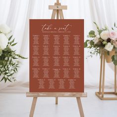 a wooden easel with a seating chart on it and flowers in the background at a wedding