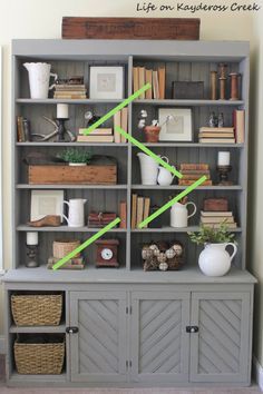 a gray bookcase with green tape on the top and bottom shelves, filled with books