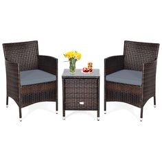 two wicker chairs and a table with flowers on it are sitting next to each other