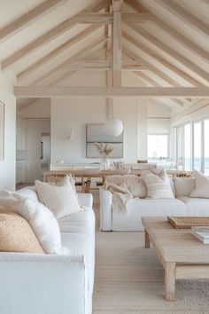 a living room filled with white furniture and lots of wooden beams on the ceiling,