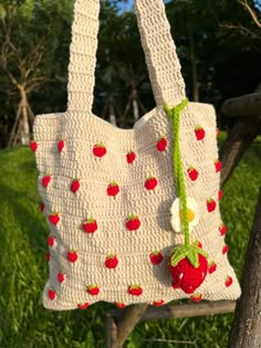 a crocheted bag hanging from a tree branch with strawberries and cherries on it