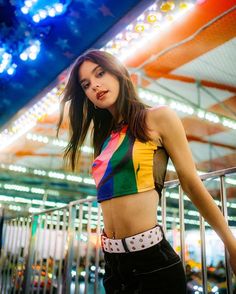 a woman standing in front of a carousel at night with her hands on her hips