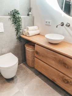 a white toilet sitting next to a wooden counter top in a bathroom under a mirror