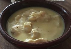 a brown bowl filled with soup on top of a wooden table