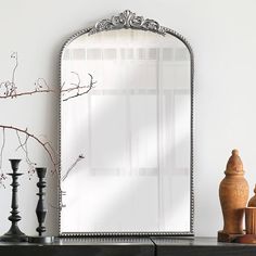 a large mirror sitting on top of a dresser next to a vase and candle holder