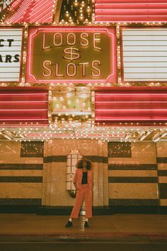 a woman standing in front of a casino with lots of neon signs on the building